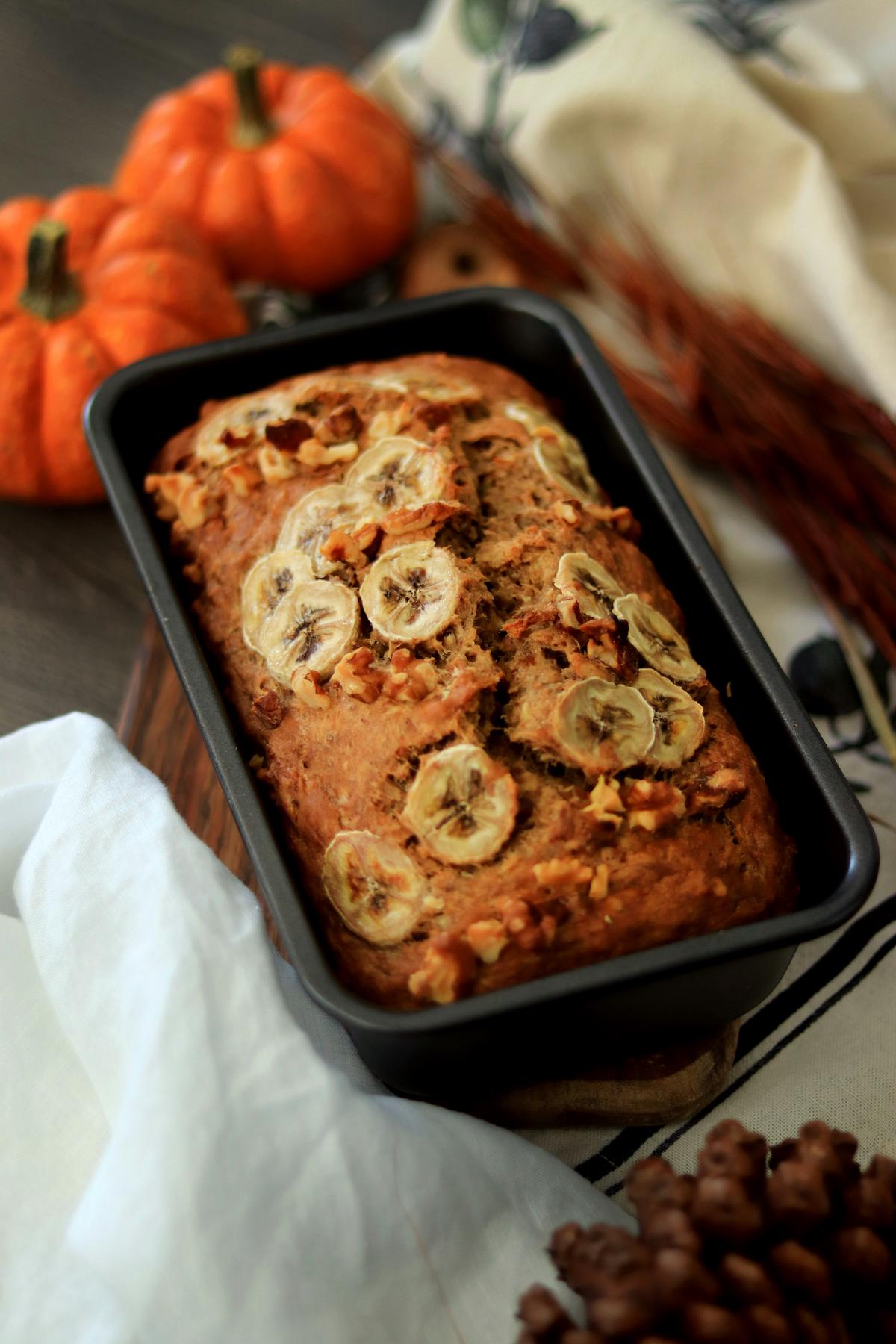 A delicious and moist banana bread loaf topped with sliced bananas.