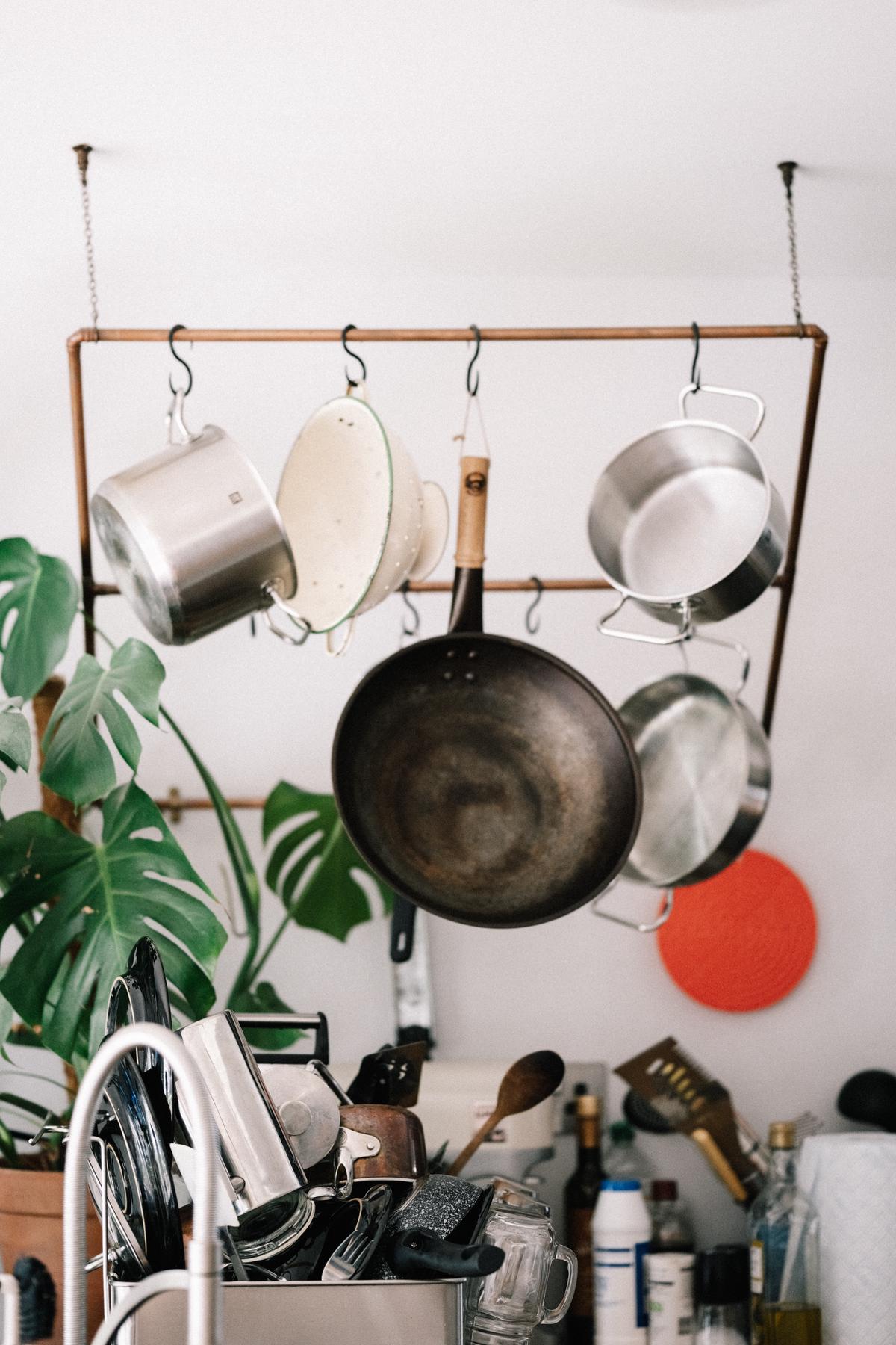 A person holding a saucepan and stirring hot butter on a stove.