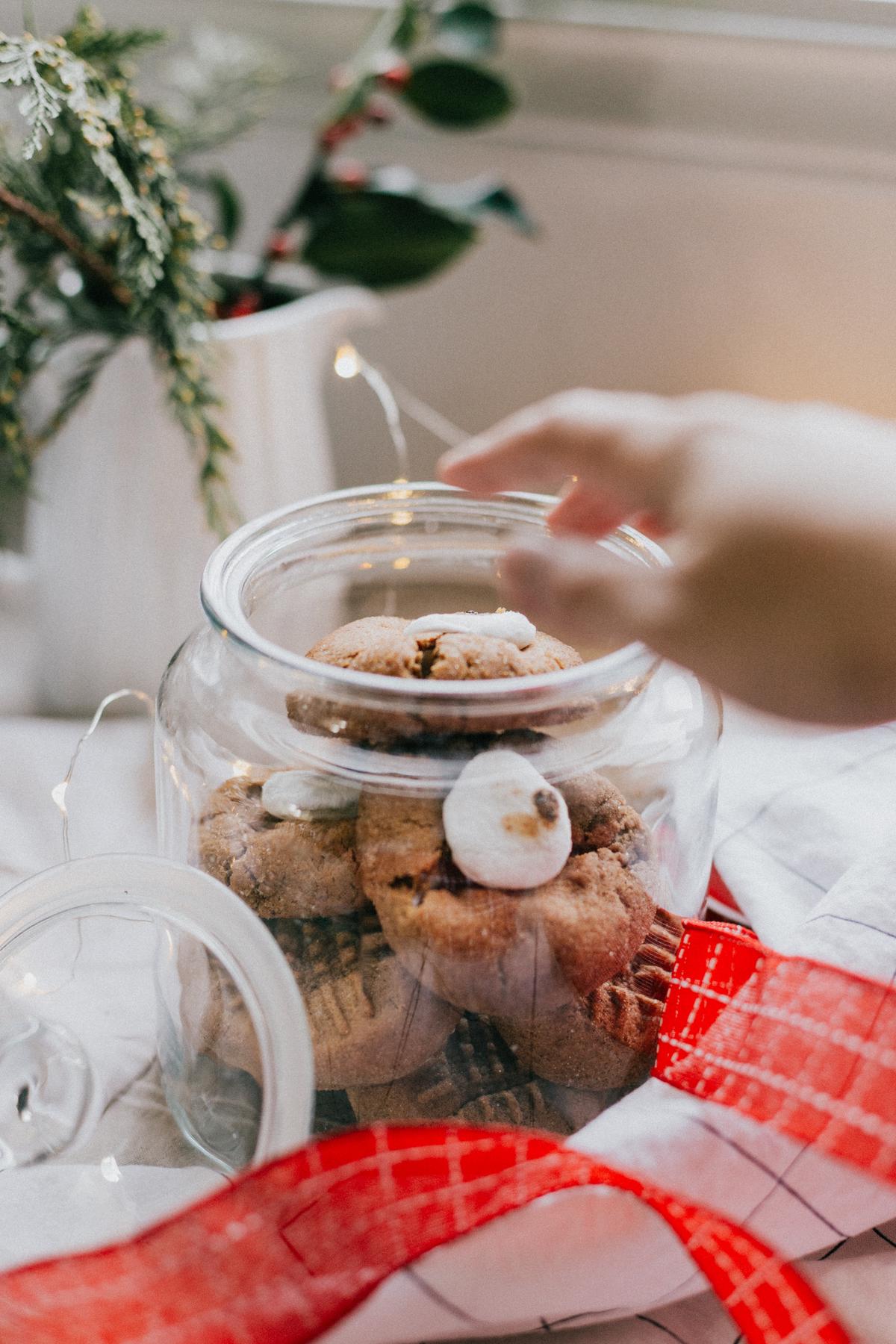 A picture of a cookie jar with various cookies spilling out of the jar and a cute cartoon chef character standing next to it holding a thumbs up sign.