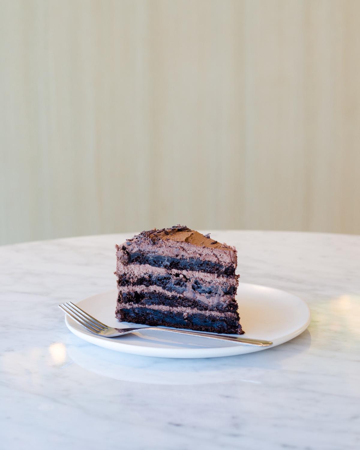 A person holding a plate with a slice of vegan cake and a spoonful of whipped cream made with a vegan egg substitute.